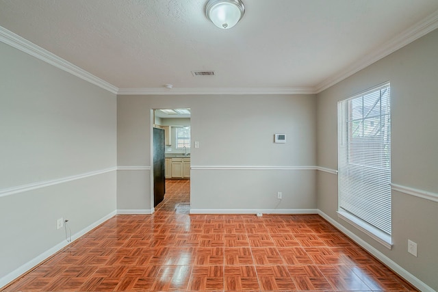 unfurnished room with a sink, baseboards, ornamental molding, and visible vents