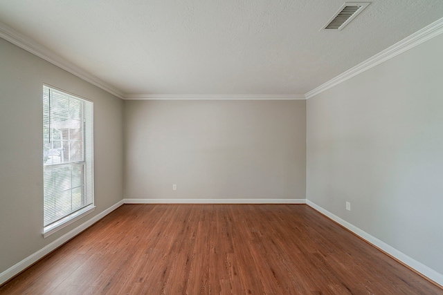 unfurnished room featuring crown molding, baseboards, wood finished floors, and visible vents