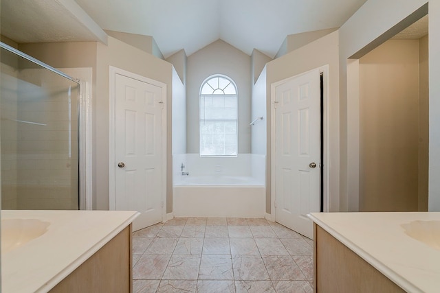 full bathroom featuring vaulted ceiling, vanity, a stall shower, and a garden tub