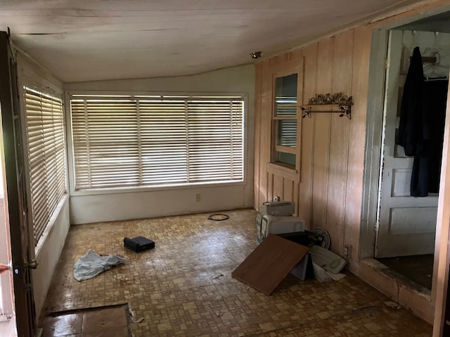 unfurnished room with wood walls and vaulted ceiling