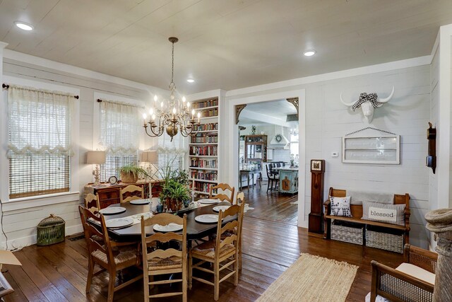 dining area featuring an inviting chandelier, recessed lighting, wooden walls, and hardwood / wood-style floors