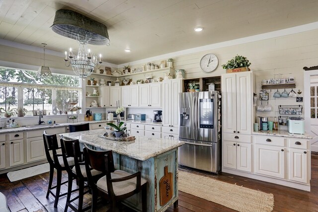 kitchen with open shelves, a sink, stainless steel fridge with ice dispenser, dark wood-type flooring, and a kitchen island