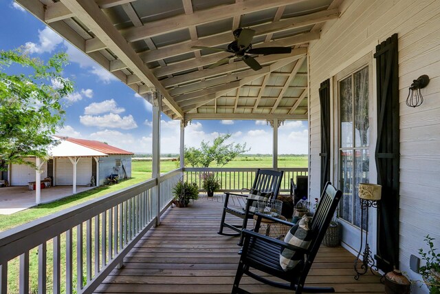 wooden terrace with a detached garage and a ceiling fan