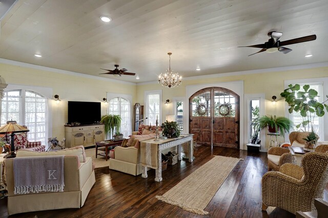 living area featuring ornamental molding, dark wood-style flooring, ceiling fan with notable chandelier, and a wealth of natural light