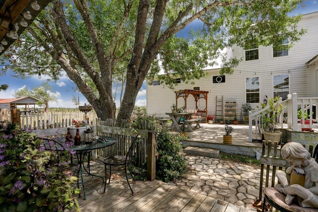 wooden terrace featuring outdoor dining area, a patio area, fence, and a pergola