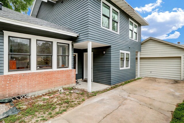 exterior space featuring a garage, an outbuilding, driveway, and brick siding