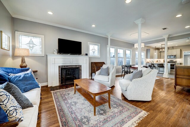 living area featuring baseboards, ornamental molding, a fireplace, and ornate columns