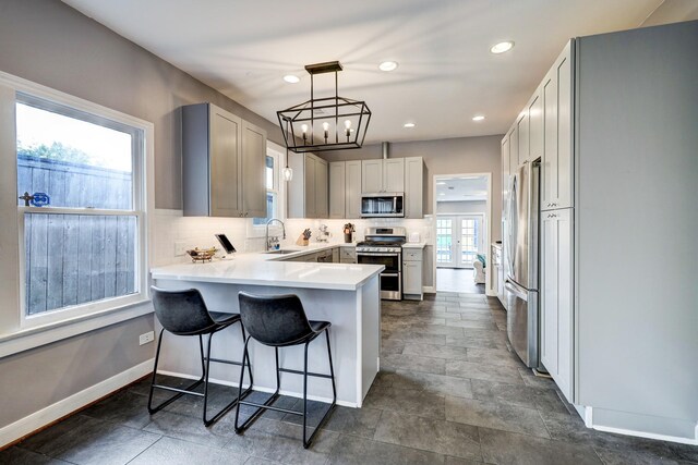 kitchen with backsplash, appliances with stainless steel finishes, a sink, a peninsula, and recessed lighting