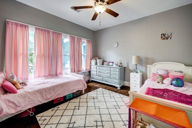 bedroom with baseboards, ceiling fan, visible vents, and wood finished floors
