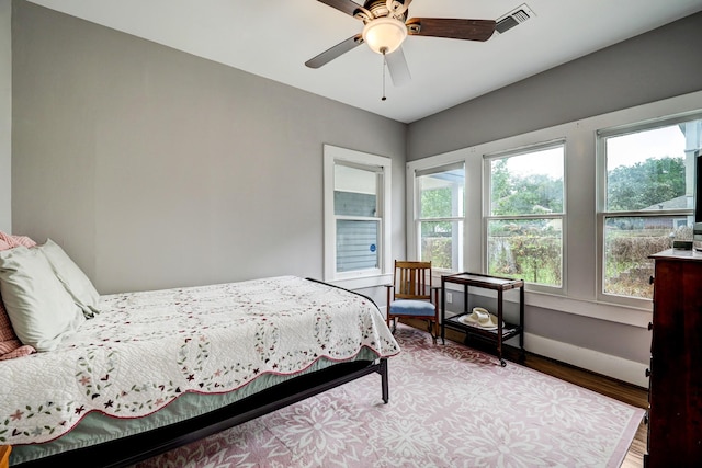 bedroom featuring visible vents, baseboards, ceiling fan, and wood finished floors