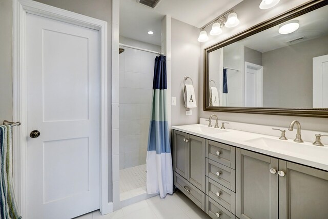 bathroom featuring tile patterned floors, visible vents, a tile shower, and a sink