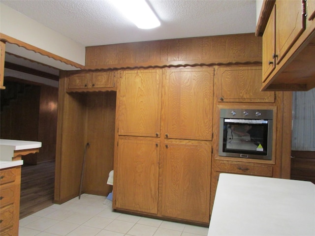 kitchen featuring brown cabinets, oven, a textured ceiling, and light countertops