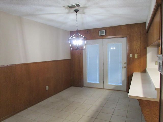 unfurnished dining area featuring wooden walls, wainscoting, and visible vents