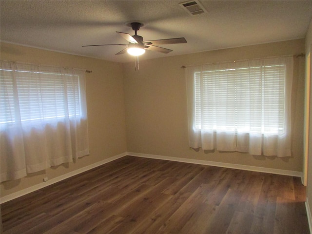 empty room featuring baseboards, ceiling fan, dark wood-style flooring, and visible vents