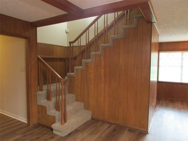 stairs featuring wood walls and wood finished floors