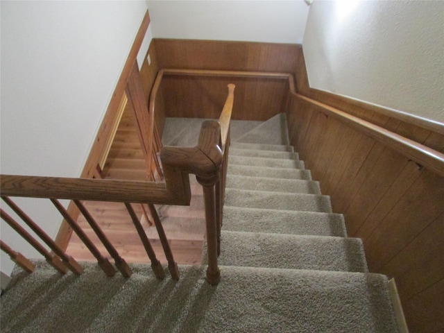 stairway with wainscoting and wood walls