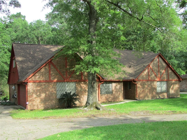 view of front of home with roof with shingles, a front lawn, and brick siding