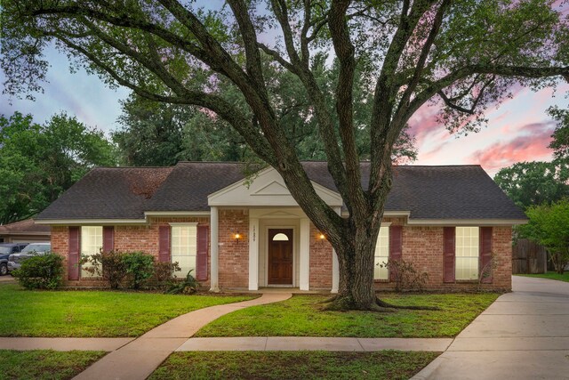 single story home with brick siding, roof with shingles, and a front lawn