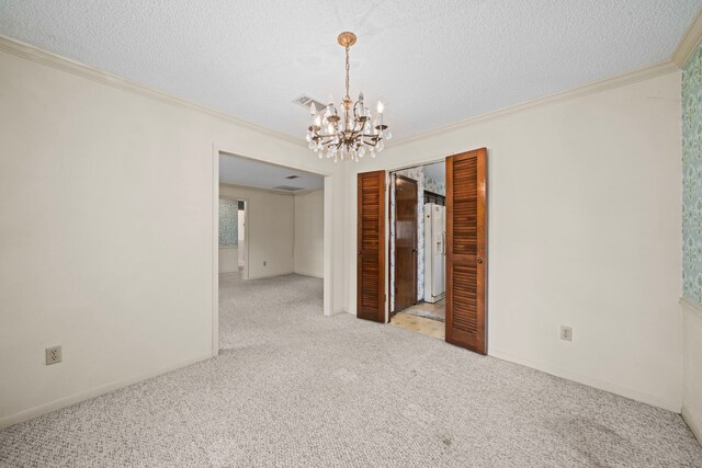 unfurnished room with a notable chandelier, carpet floors, a textured ceiling, visible vents, and ornamental molding
