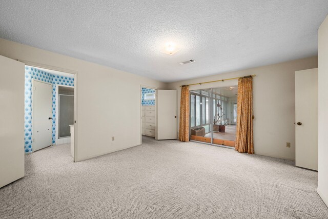 unfurnished bedroom featuring carpet floors, a textured ceiling, visible vents, and access to exterior