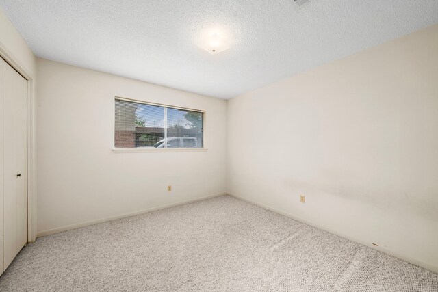 unfurnished bedroom featuring carpet floors, a textured ceiling, baseboards, and a closet