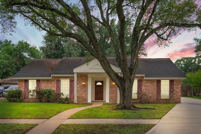 ranch-style house featuring brick siding, a shingled roof, and a front yard