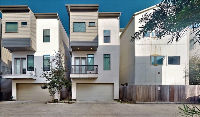 view of front of property with concrete driveway, fence, stucco siding, and an attached garage