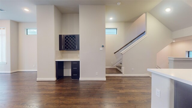 unfurnished living room with recessed lighting, dark wood finished floors, a dry bar, and plenty of natural light