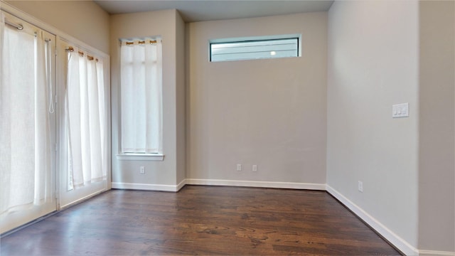empty room featuring baseboards and dark wood finished floors