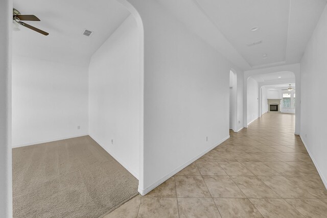 hall featuring arched walkways, baseboards, light tile patterned flooring, and visible vents