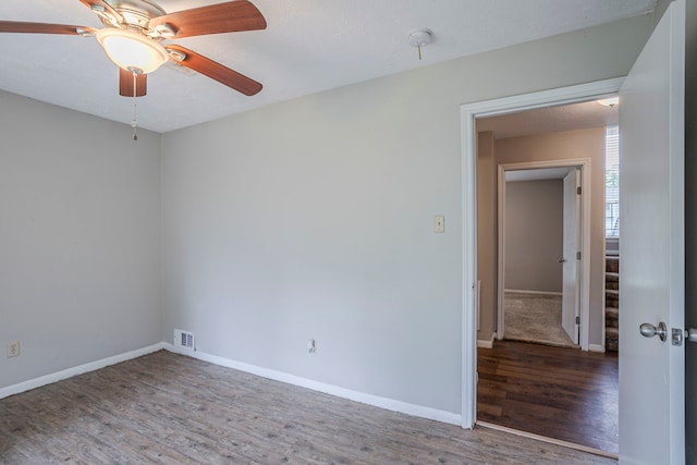 spare room featuring baseboards, a ceiling fan, wood finished floors, and visible vents