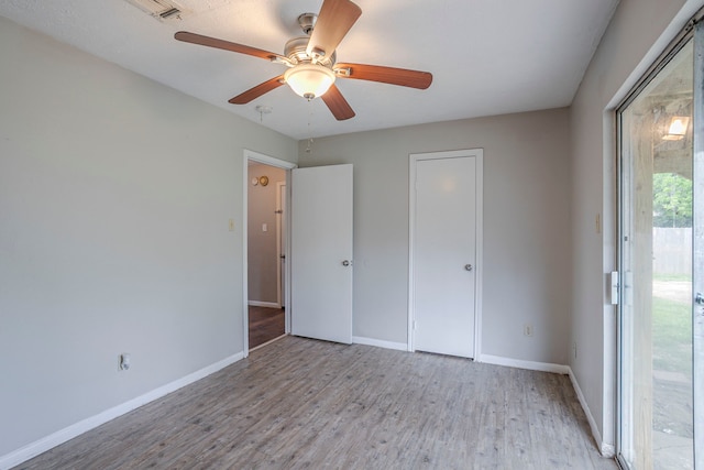 unfurnished bedroom with baseboards, ceiling fan, wood finished floors, and visible vents