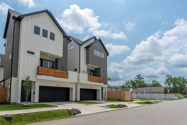 contemporary house with an attached garage, board and batten siding, fence, and driveway