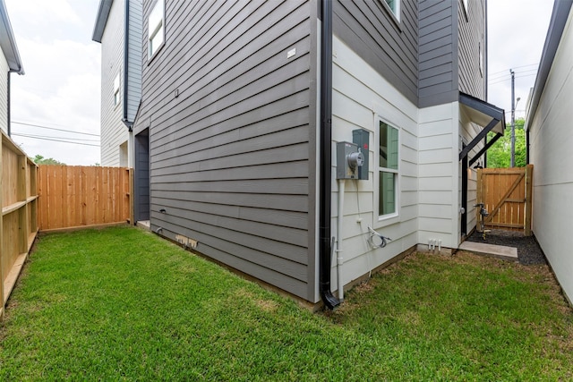 view of side of property featuring a fenced backyard, a gate, and a lawn