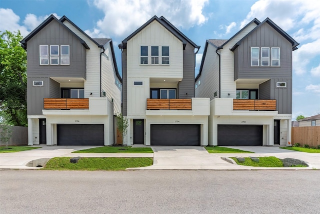 view of front facade with concrete driveway, board and batten siding, an attached garage, and a balcony