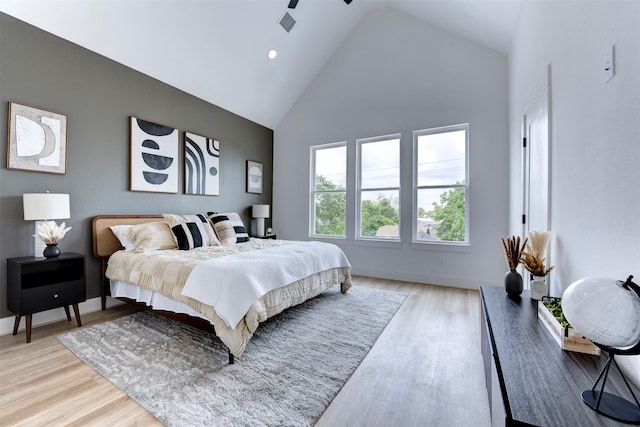 bedroom featuring high vaulted ceiling, baseboards, and light wood-type flooring