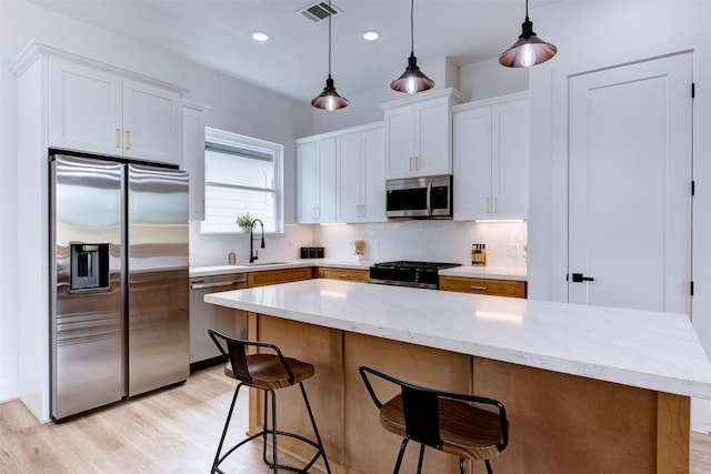 kitchen featuring visible vents, light wood-style floors, white cabinetry, tasteful backsplash, and appliances with stainless steel finishes
