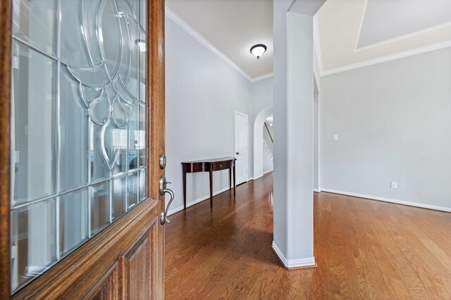entryway with dark wood-style flooring, arched walkways, baseboards, and ornamental molding