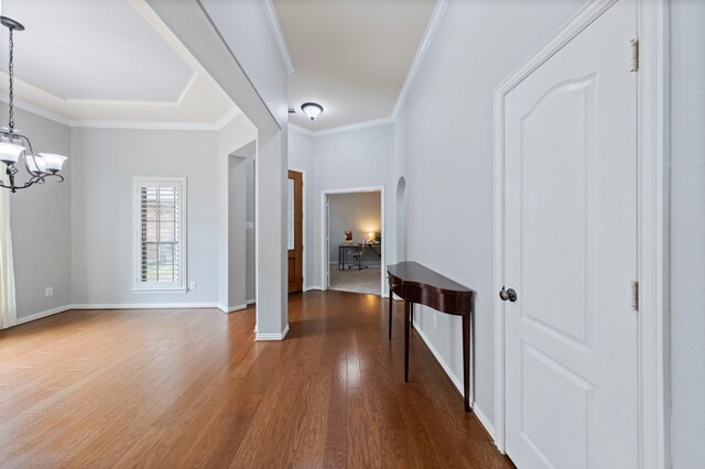entryway featuring baseboards, ornamental molding, wood finished floors, and a chandelier