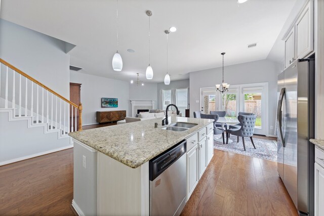 kitchen featuring an inviting chandelier, a sink, a kitchen island with sink, dark wood finished floors, and stainless steel appliances