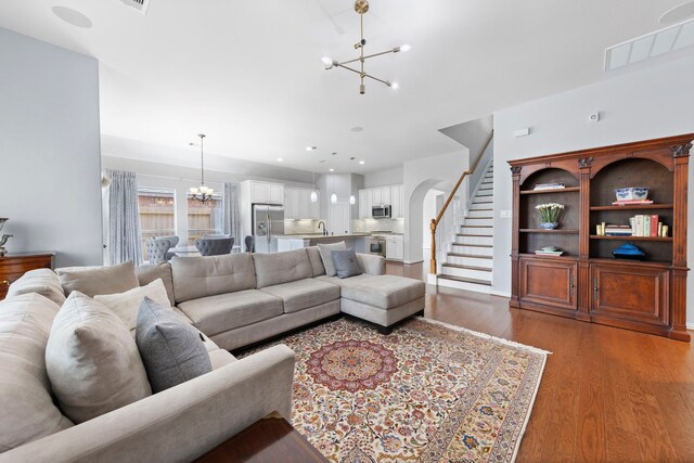 living room with visible vents, wood finished floors, stairway, a notable chandelier, and recessed lighting