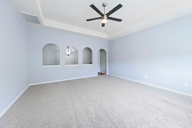 carpeted spare room with a ceiling fan, baseboards, visible vents, and a raised ceiling