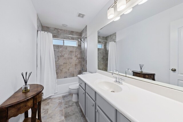 full bath with visible vents, shower / bath combo, toilet, and vanity