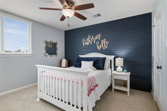 carpeted bedroom with baseboards, ceiling fan, an accent wall, and visible vents