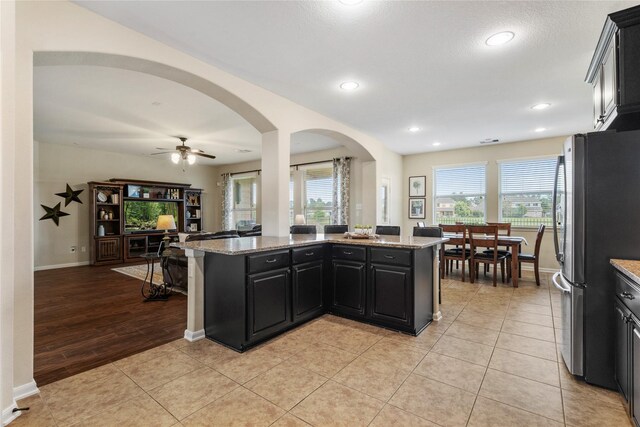kitchen with a healthy amount of sunlight, ceiling fan, freestanding refrigerator, and light stone countertops