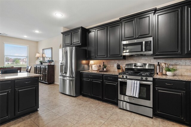 kitchen featuring appliances with stainless steel finishes, dark cabinetry, and decorative backsplash