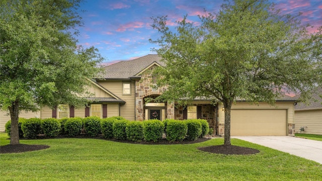 traditional-style house with a garage, a front yard, driveway, and stone siding