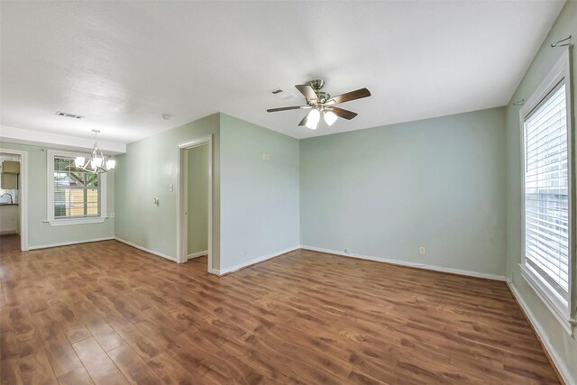 unfurnished room featuring baseboards, ceiling fan with notable chandelier, wood finished floors, and visible vents