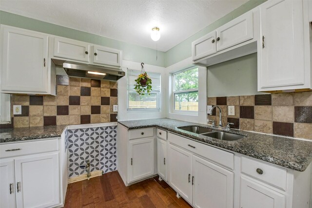 kitchen with dark wood-style flooring, a sink, white cabinets, dark stone countertops, and under cabinet range hood