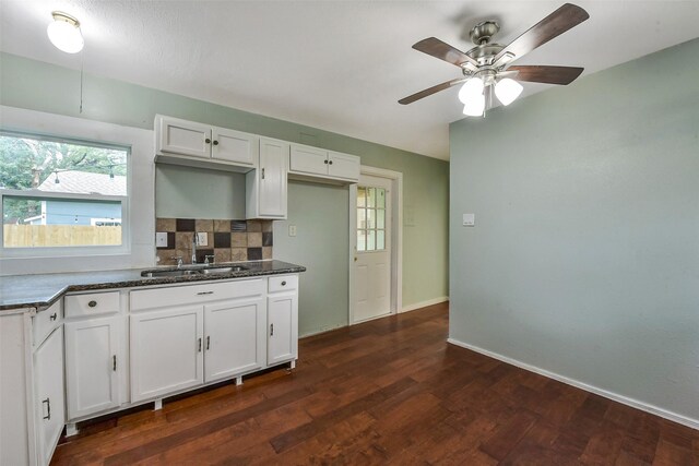 kitchen featuring ceiling fan, a sink, white cabinetry, decorative backsplash, and dark wood-style floors